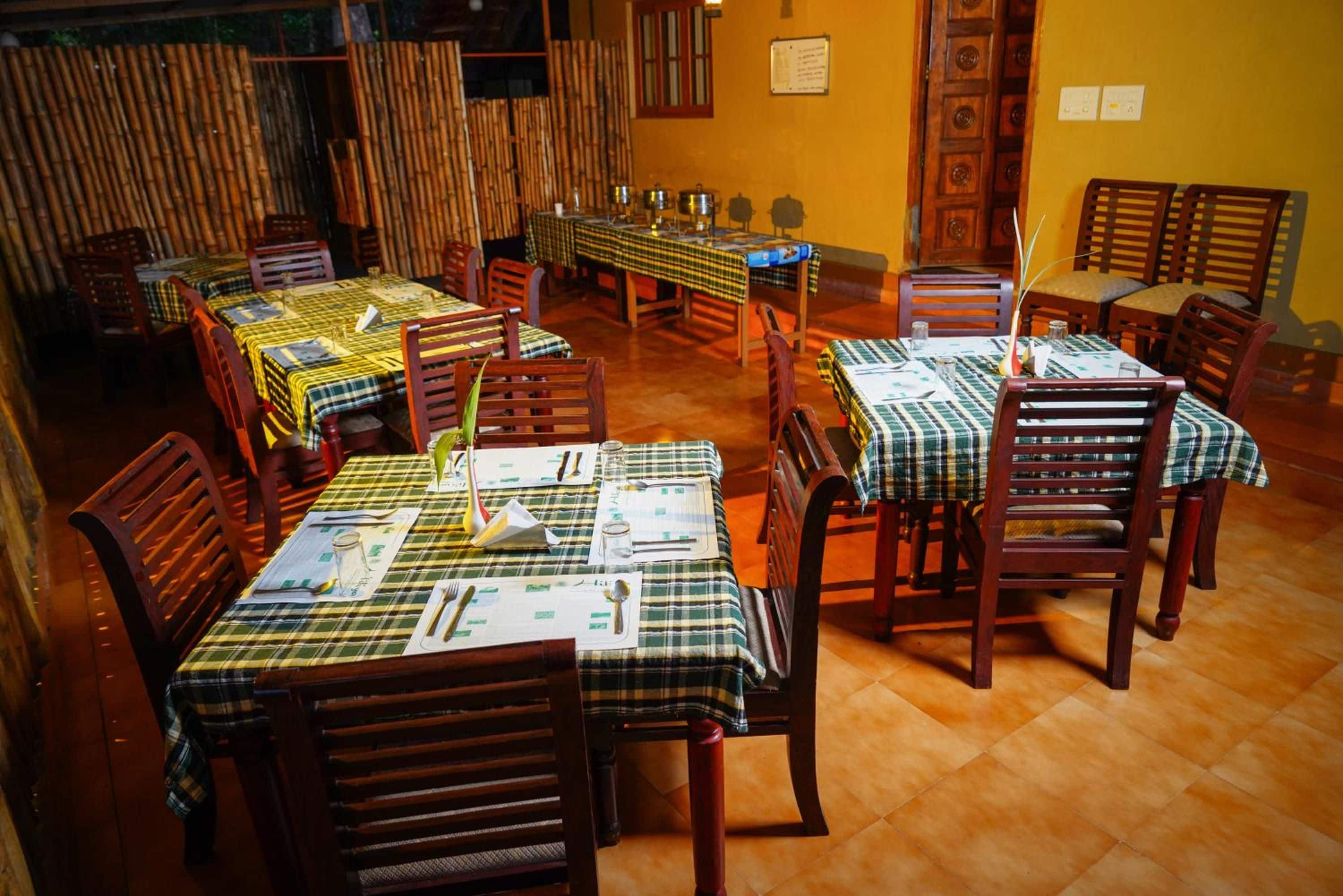 Ein Restaurant mit mehreren Tischen, die mit karierten Tischdecken bedeckt sind, Holzstühlen und einem Fliesenboden.