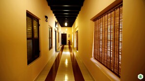 A hallway with a striped floor, wooden doors, and a window with blinds. - Hiliya Resort - Hostel (Sulthan Bathery)