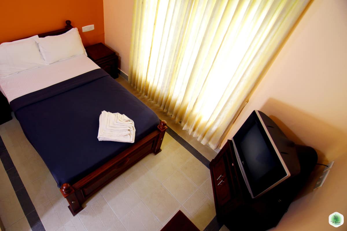 A hotel room with a bed, a TV, and a nightstand.