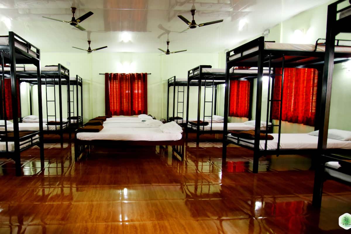 A room with bunk beds arranged in two rows, ceiling fans, and red curtains.
