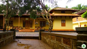 A traditional building with a tiled roof, a central entrance, and a courtyard with a stone pathway. - Hiliya Resort - Hostel (Sulthan Bathery)