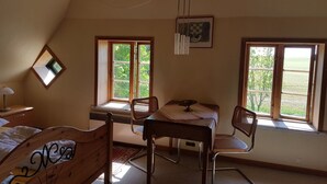 Une chambre à coucher avec un lit, un bureau, deux chaises et une fenêtre.