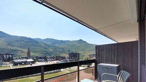 A balcony with a view of mountains, a train, and buildings. - Aravis 314 by Interhome (Les Menuires)