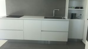 A modern kitchen with a built-in sink, a countertop, and a shelf with a computer and a green object. - New terrace sea view villa (Augusta)