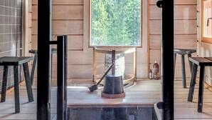 A wooden cabin interior with a large window, a wooden table, and a chair.