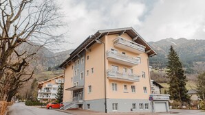 Ein mehrstöckiges Hotel mit Balkonen, einem Parkplatz und einer Bergkulisse.