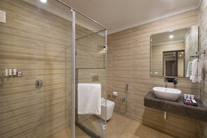 Un baño moderno con cabina de ducha de vidrio, un lavabo blanco y un espejo grande.