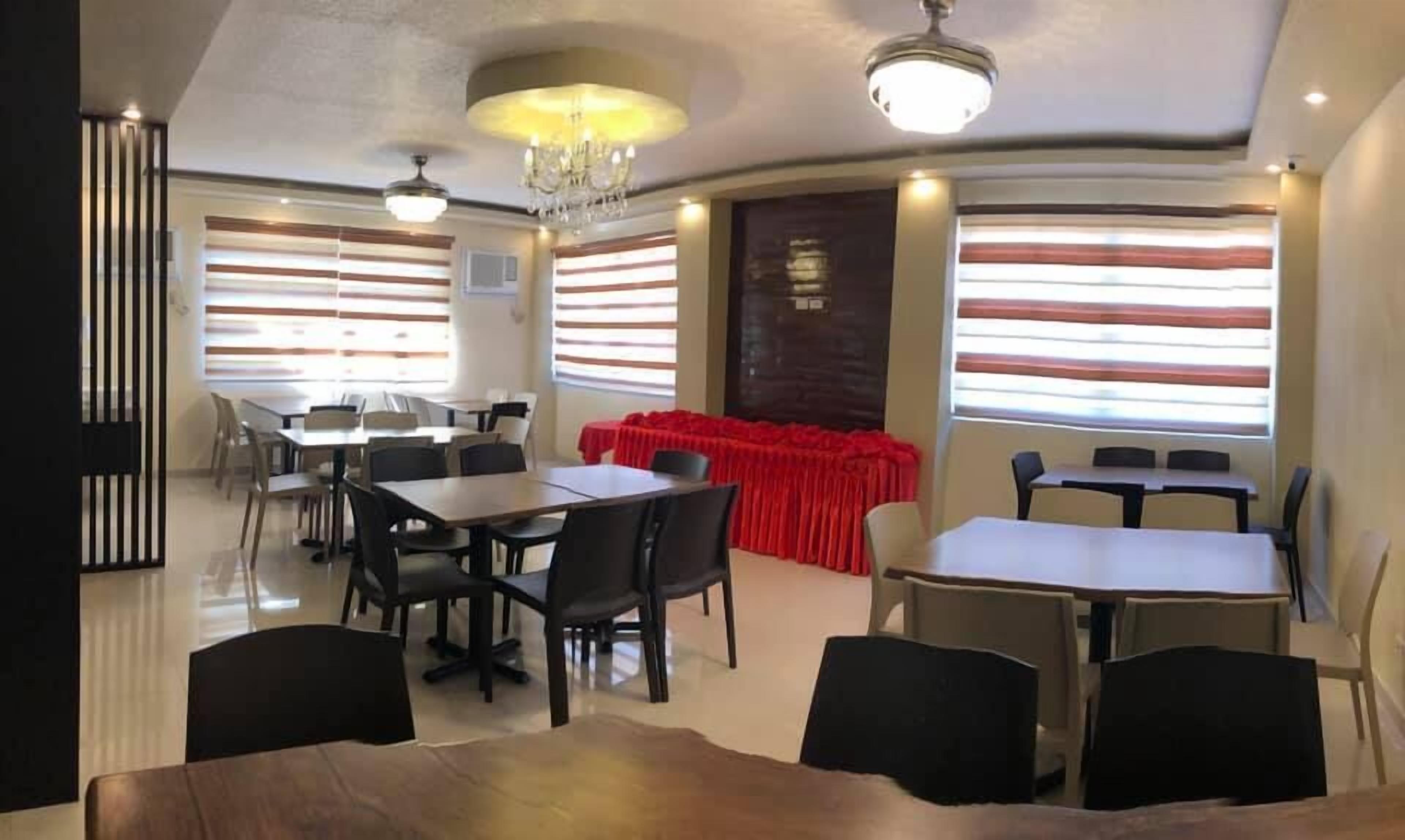 A conference room with tables and chairs, a red tablecloth-covered table, and large windows with blinds.