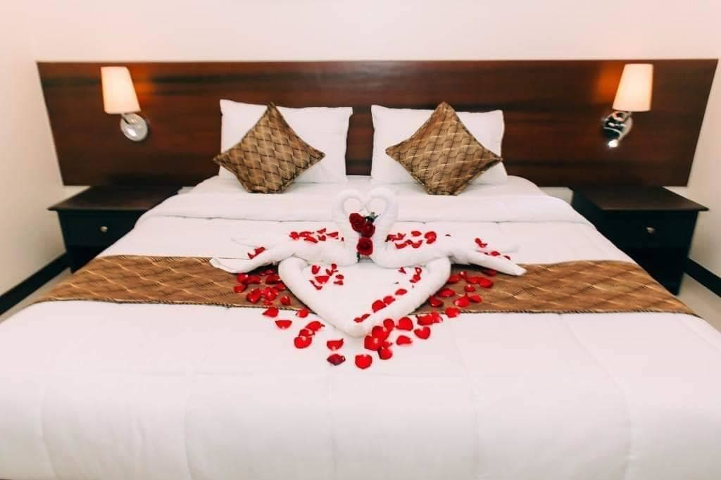 Ein ordentlich bezogenes Bett mit einer herzenförmigen Anordnung aus Rosenblättern und einer Schwaneinrichtung.