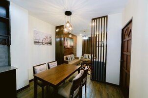 Un comedor con una mesa y sillas de madera, un sofá y un adorno en la pared.