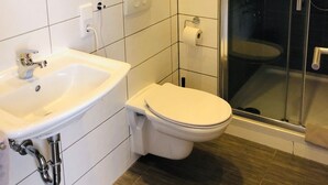 Un baño moderno con lavamanos, inodoro y cabina de ducha de vidrio.