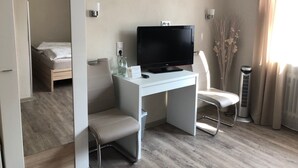 Habitación de hotel con cama, escritorio con televisor, una silla y un calefactor.
