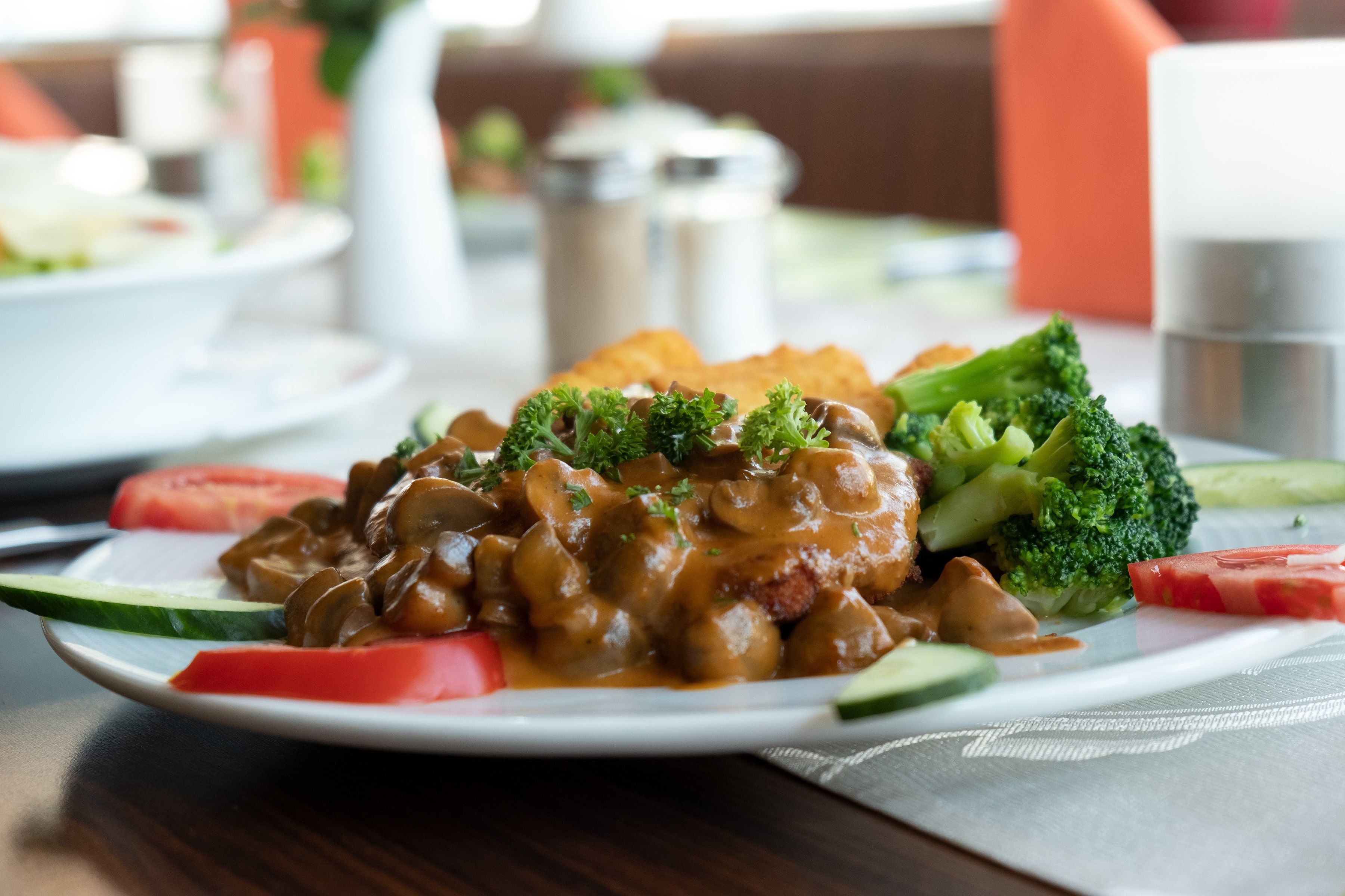 Une assiette de nourriture contenant des champignons, des brocolis et des tomates.