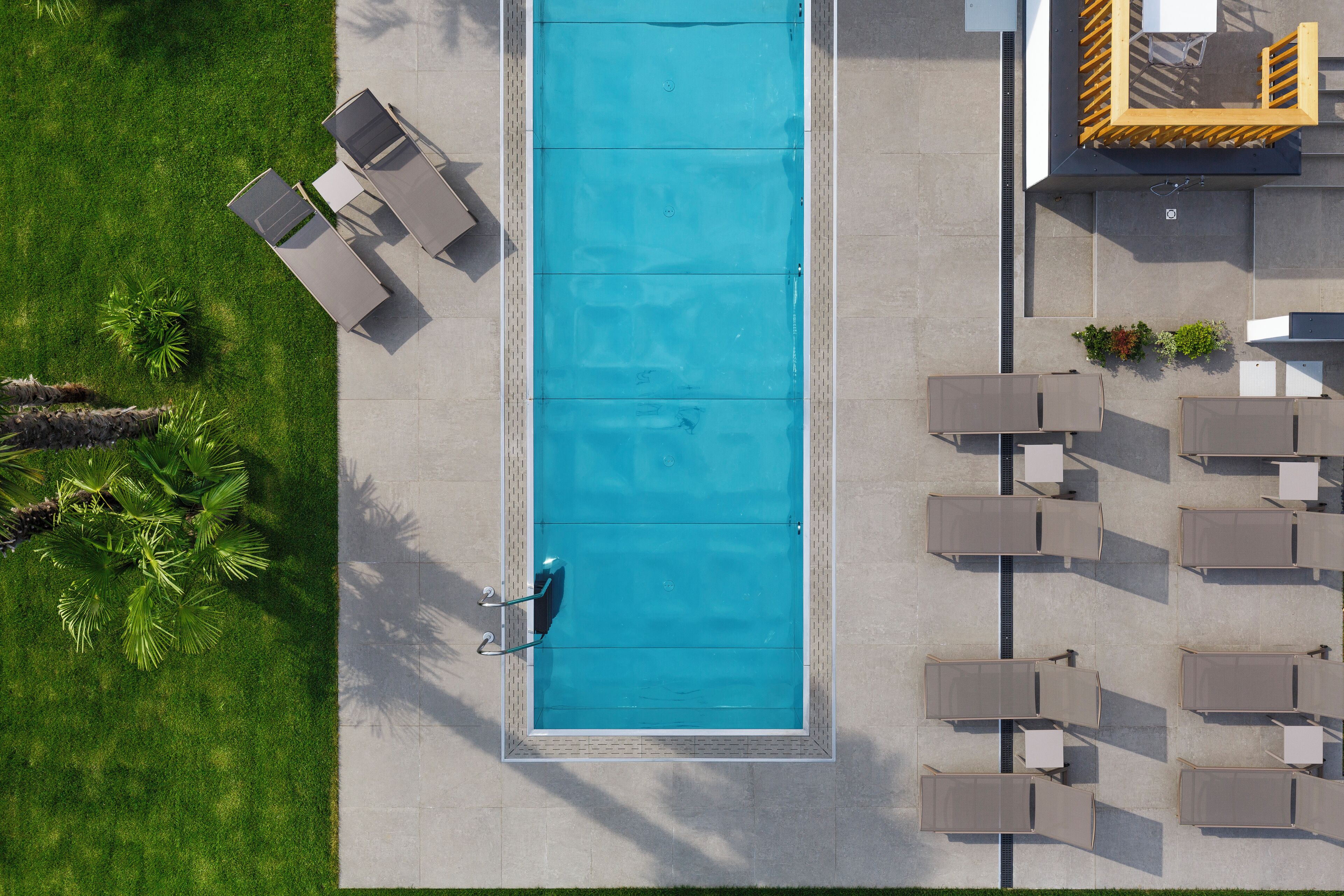 An aerial view of a swimming pool with adjacent lounge chairs and a small garden area.