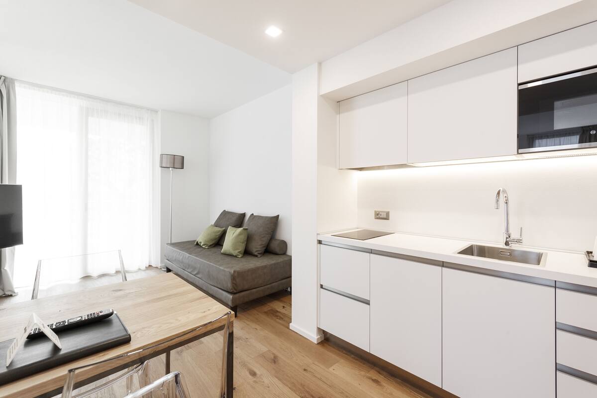 A modern kitchen with white cabinets, a built-in oven, and a sink.