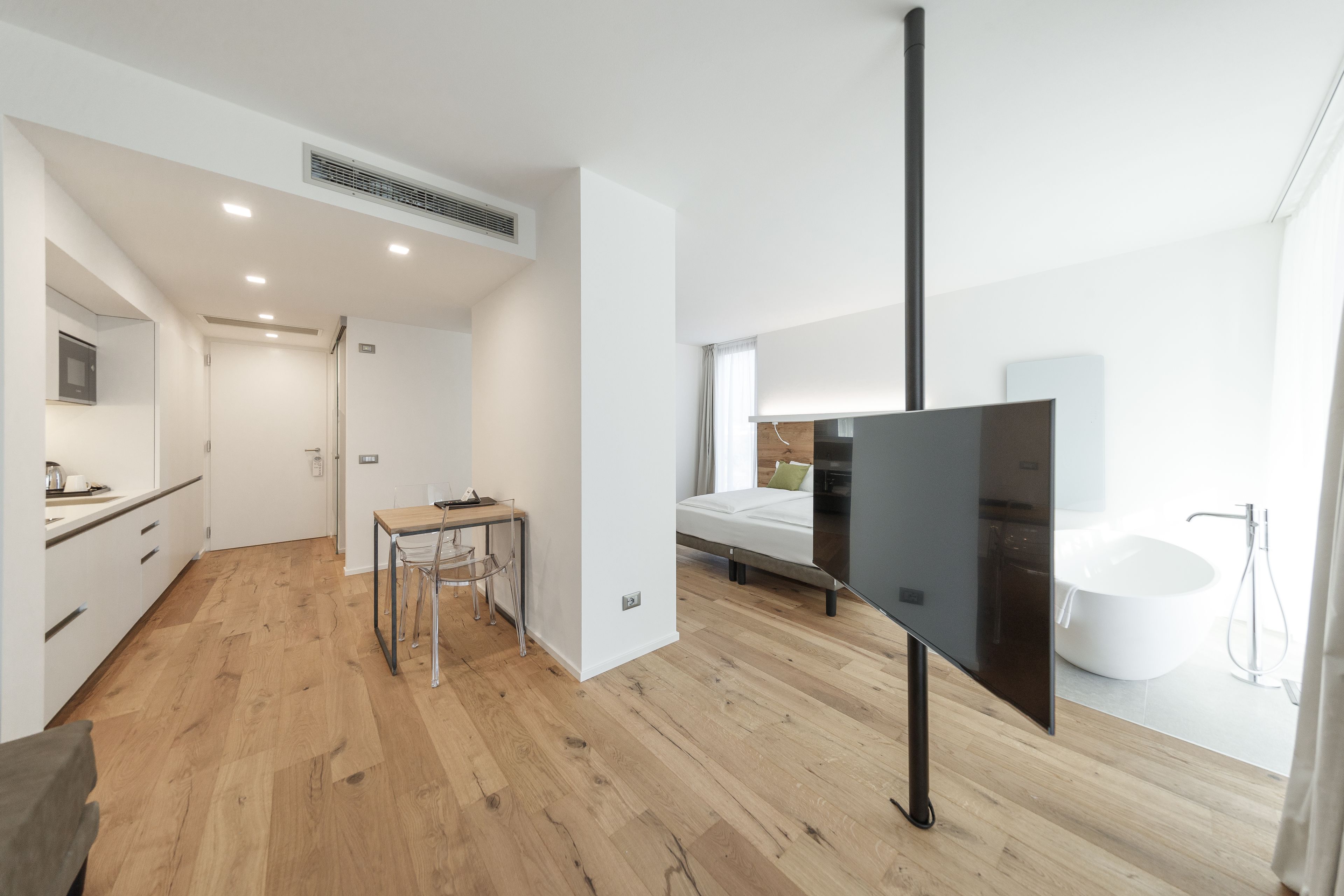 A modern apartment with a kitchen, dining area, and a bedroom with a large window.