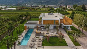 A modern two-story house with a swimming pool, outdoor seating, and a garden. - Alea Garda Lake Suite (Arco)