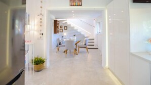 Una cucina moderna con frigorifero integrato, un'area pranzo con tavolo e sedie, e una scala che conduce a un altro piano.