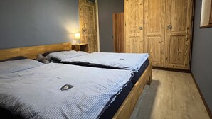 Een slaapkamer met twee bedden, houten kasten en een nachtkastje met een lamp.
