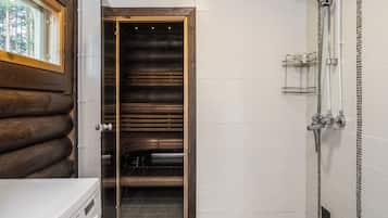 A bathroom with a wooden door, a shower, and a tiled floor.
