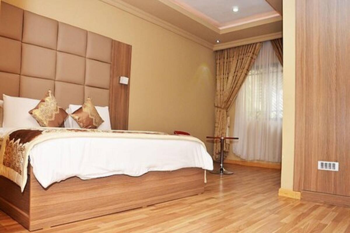 A bedroom with a large bed, wooden headboard, and a bedside table.