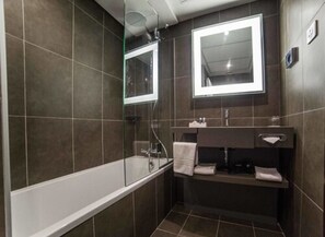 A modern bathroom with a glass-enclosed shower, a white bathtub, and a dark vanity with a mirror. - Royal Choice Inn (Abuja)