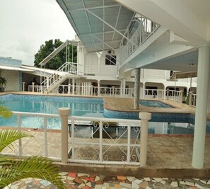 A pool area with a covered deck, stairs leading to an upper level, and a tiled floor. - Royal Choice Inn (Abuja)