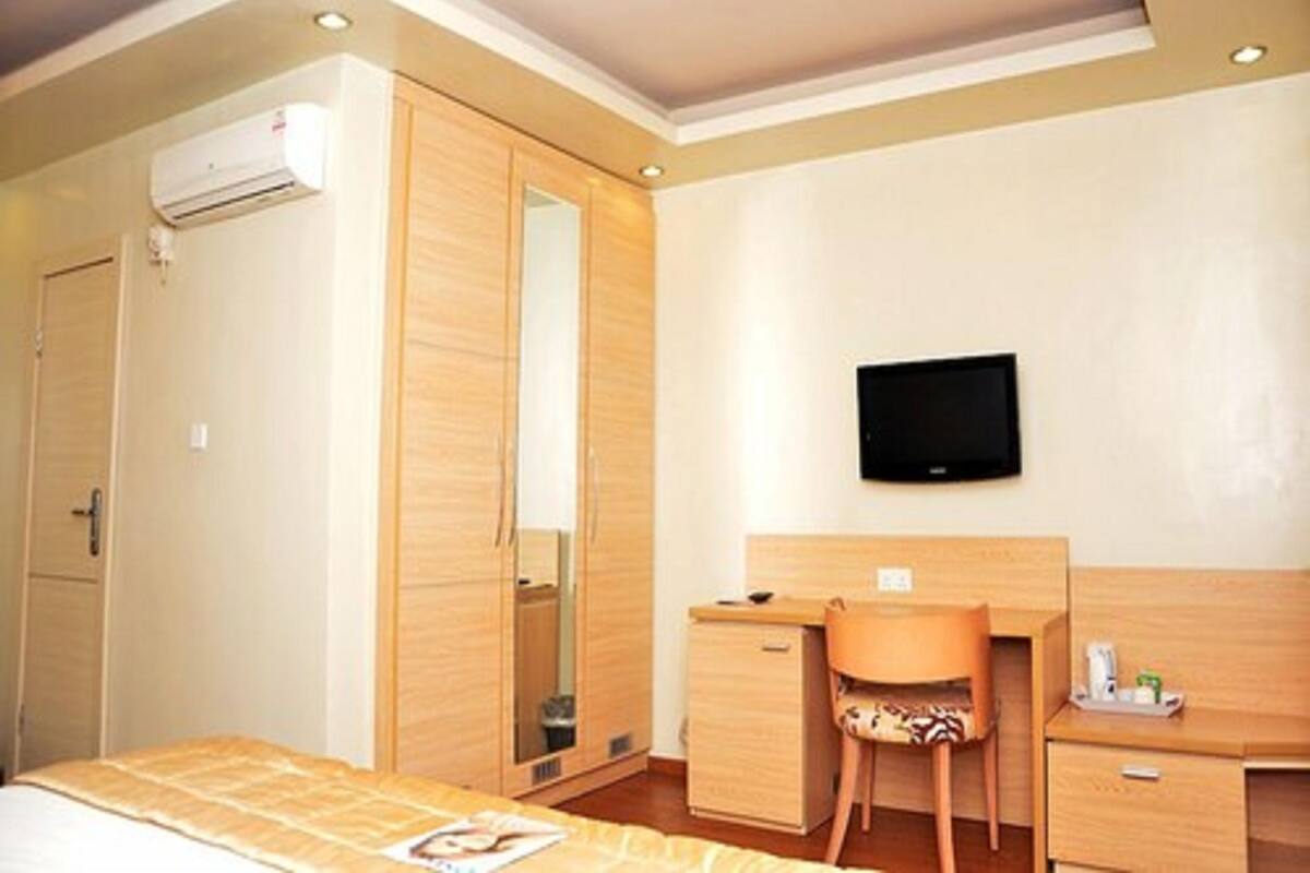 A bedroom with a bed, a desk, a chair, a television, and a wardrobe.