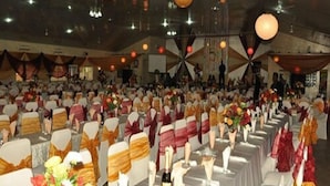 Une salle de banquet avec des rangées de tables, chacune recouverte d’une nappe blanche et agrémentée d’un centre de table.