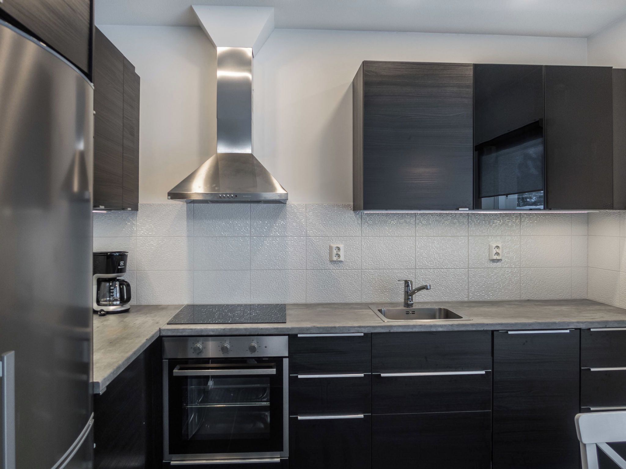 Una cocina moderna con electrodomésticos de acero inoxidable, horno empotrado y campana extractora.
