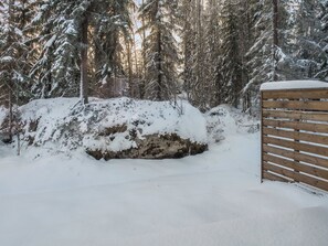 Paesaggio innevato con un cancello di legno e alberi sempreverdi fitti.