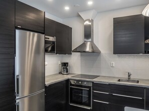 Una cucina moderna con elettrodomestici in acciaio inossidabile, forno integrato e cappa aspirante.