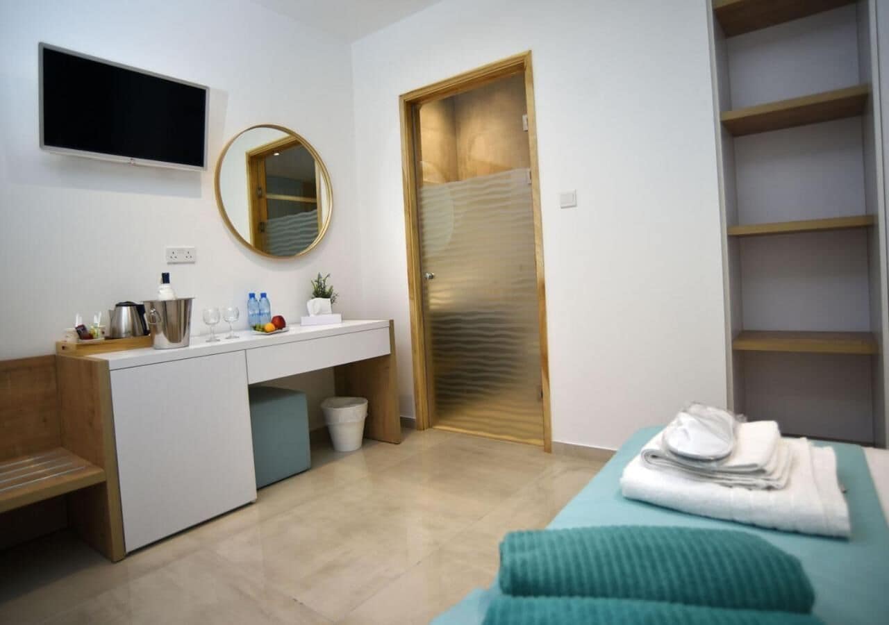 A modern bedroom with a bed, a bedside table, a TV, a mirror, and a wardrobe.