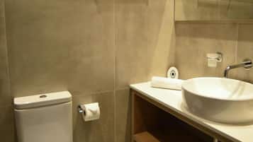 A modern bathroom with a toilet, sink, and mirror.