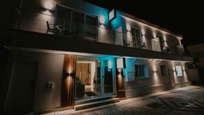 A modern two-story building with a glass entrance, outdoor seating, and a balcony. - Hai Hotel (Larnaca)