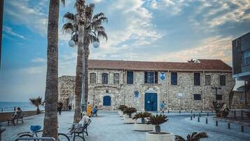 A courtyard with stone buildings, palm trees, and a paved walkway.