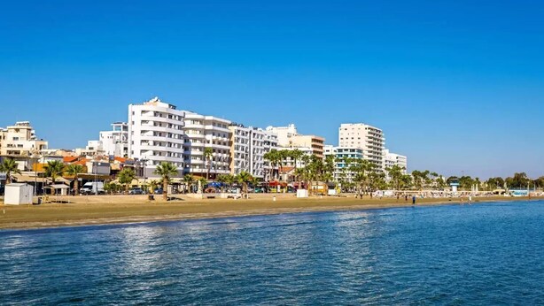 A coastal hotel with multiple floors, a beach in the foreground, and palm trees. - Hai Hotel (Larnaca)