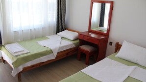 A hotel room with two single beds, a wooden dresser, a mirror, and a small stool. - Hisarlik Hotel (Çanakkale)