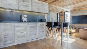 Une cuisine moderne avec des meubles en bois, une cuisinière encastrée et un coin repas comprenant une table et des chaises.