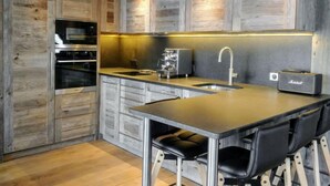 Une cuisine moderne avec des meubles en bois, un four encastré, un évier et un coin bar avec des tabourets.