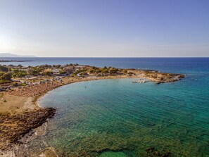 A coastal town with a beach, clear blue waters, and a mix of residential and commercial buildings.