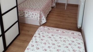 Une petite chambre à coucher, bien rangée, avec un lit, une chaise et un radiateur.