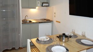 Eine kleine Küche mit Spüle, Toaster und Mikrowelle. Ein Esstisch ist gedeckt mit Tellern, Gläsern und Besteck.