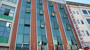 A hotel with a modern facade, multiple windows, and flags. - Sadikoglu Oteli (Artvin)