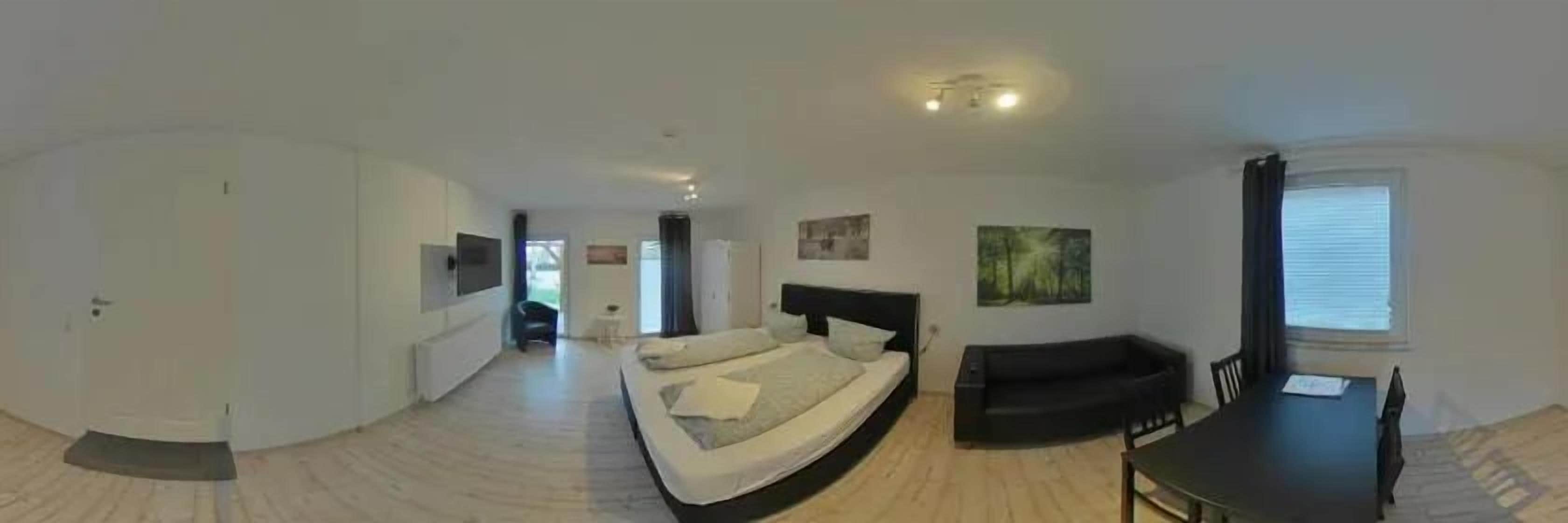 A room with a bed, a sofa, a dining table, and a TV.