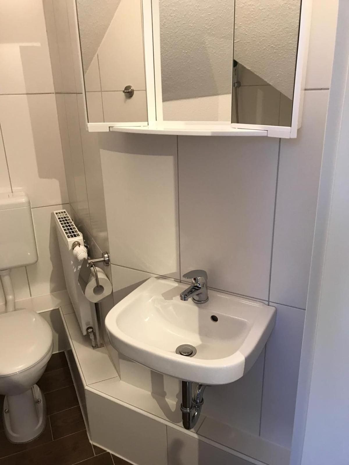 Un baño con inodoro, lavabo y espejo sobre el lavabo.