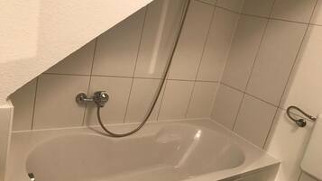 Ein Badezimmer mit einer Badewanne, einer Duschbrause und einer Toilette.