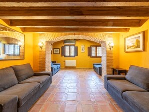 Een gezellig interieur met een stenen vloer, twee banken, een open haard en een houten plafond.