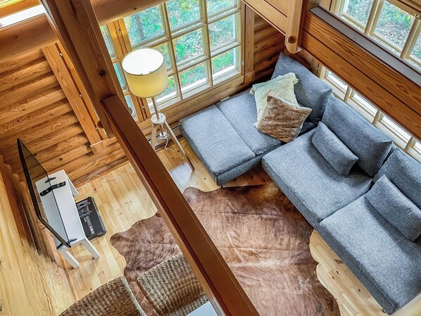 A cozy cabin interior with a sofa, a lamp, and a fireplace.