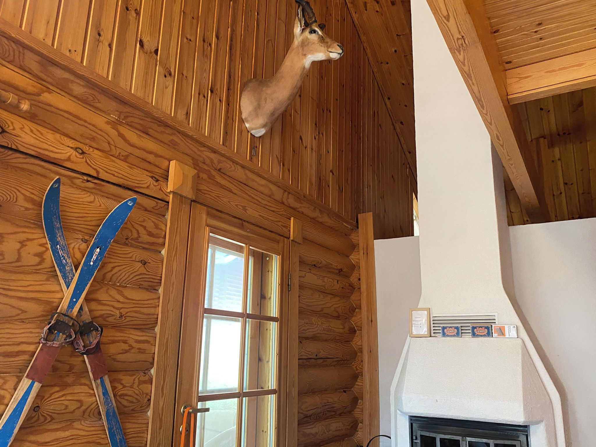 Ein rustikales Blockhaus-Interieur mit einem aufgehängten Hirschgeweih, einem Fenster und einem Kamin.